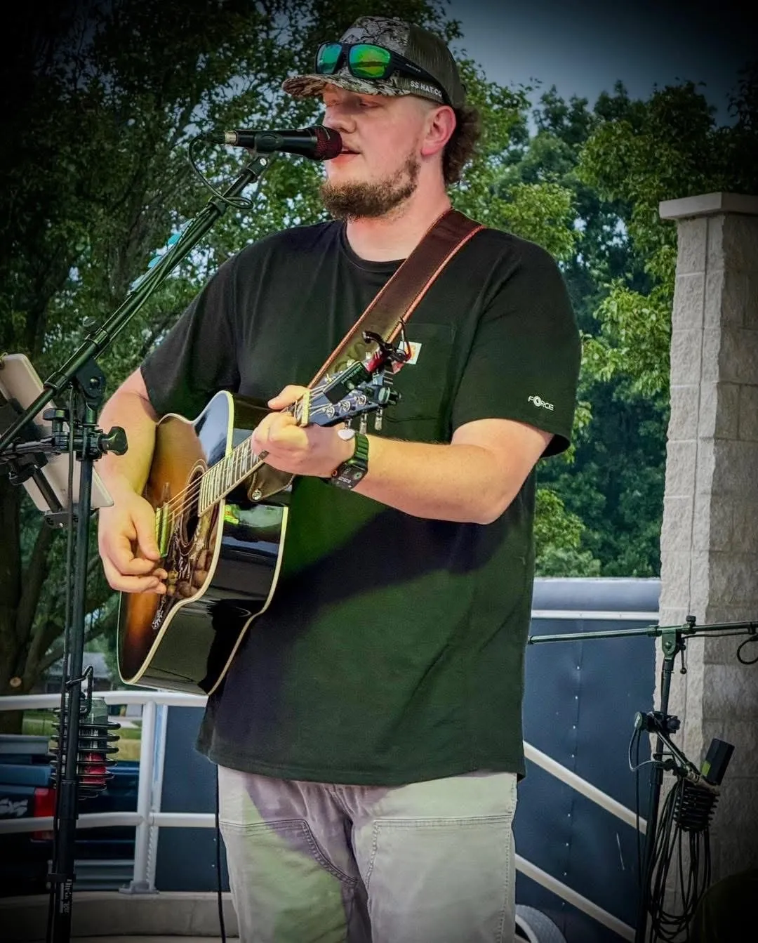 Isaac Buschur singing and playing acoustic guitar at an outdoor show