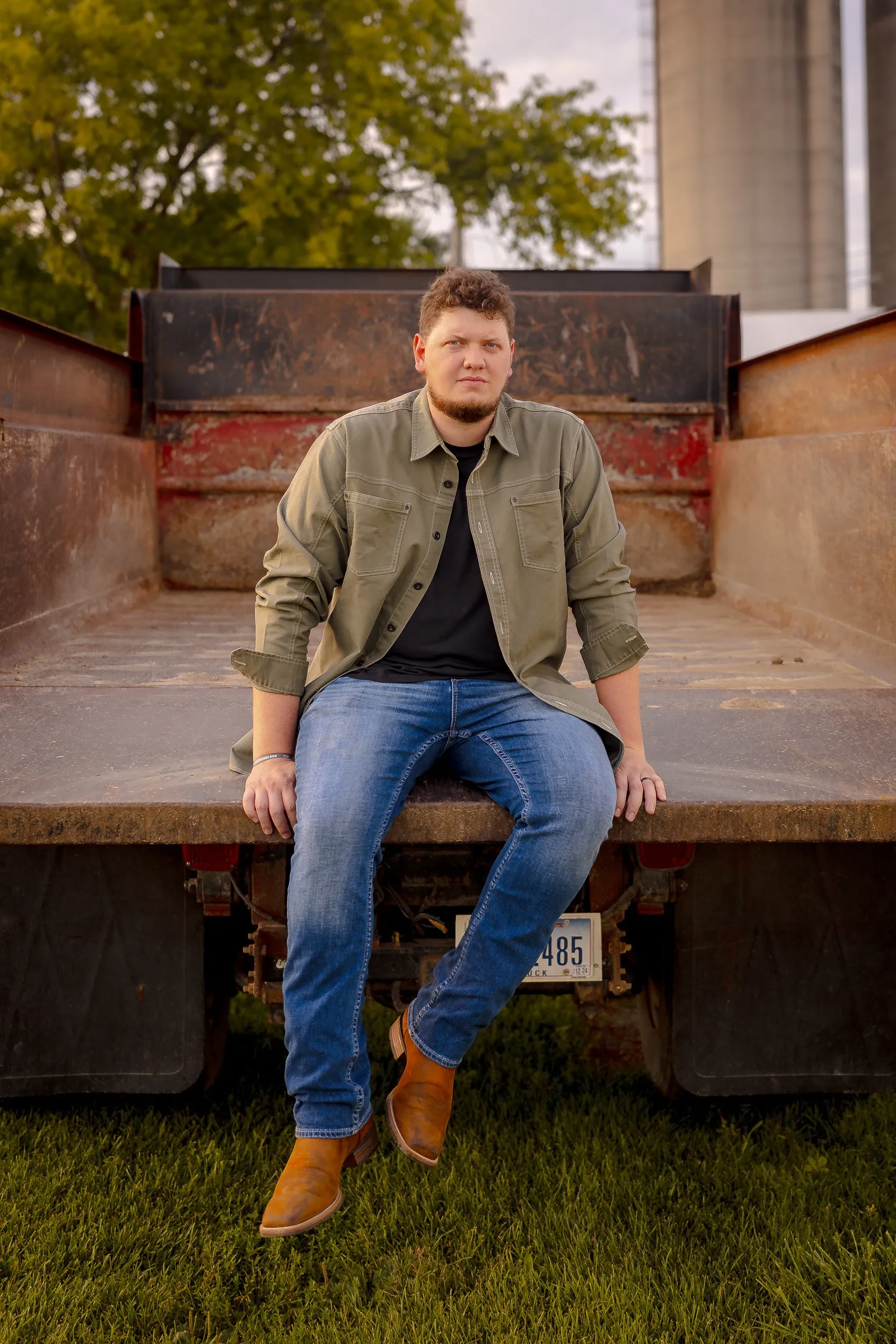 Isaac Buschur sitting on the tailgate of a farm truck